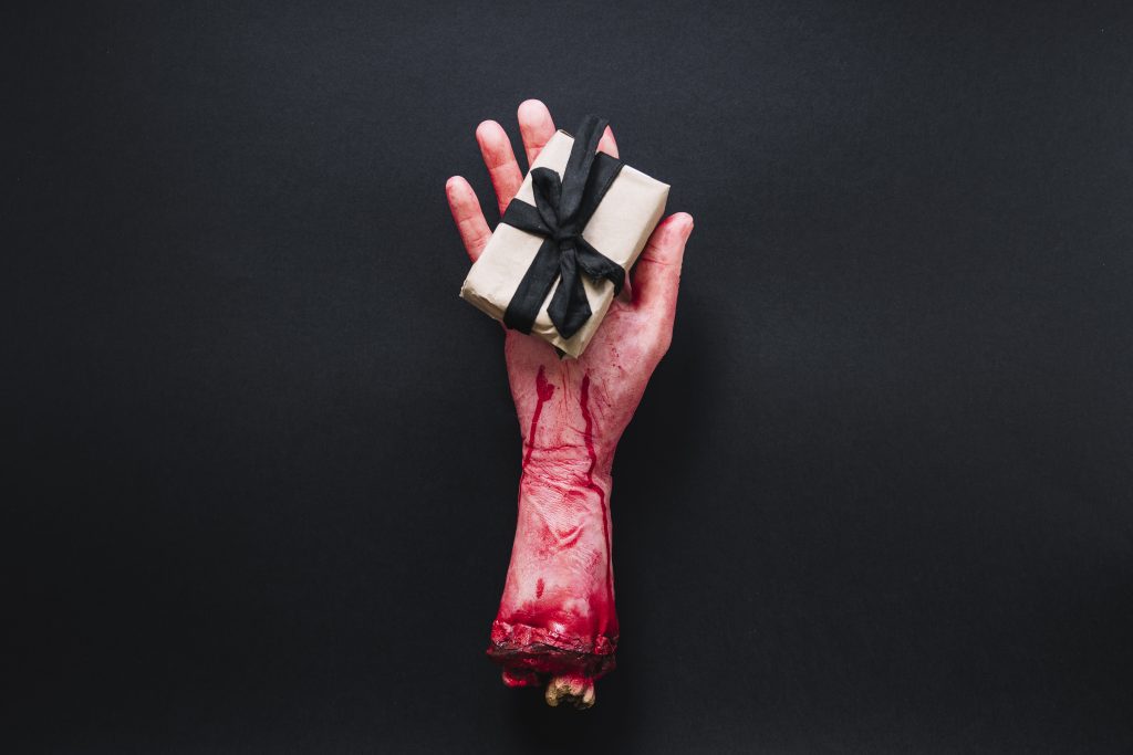 A severed bloody hand tied with a gift ribbon on black background — representing shocking crime symbolism, dark irony, and true crime narrative twists.

